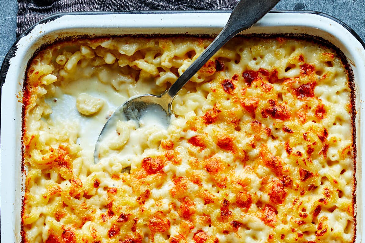 An overhead image of macaroni and cheese baked into a metal pan. A single serving is removed from one corner.