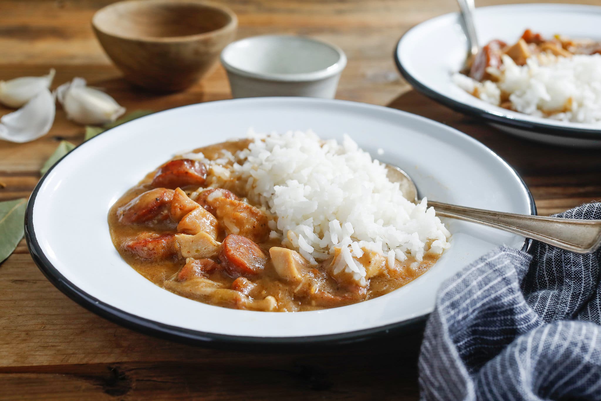 A side image of gumbo served with rice in a white rimmed bowl.