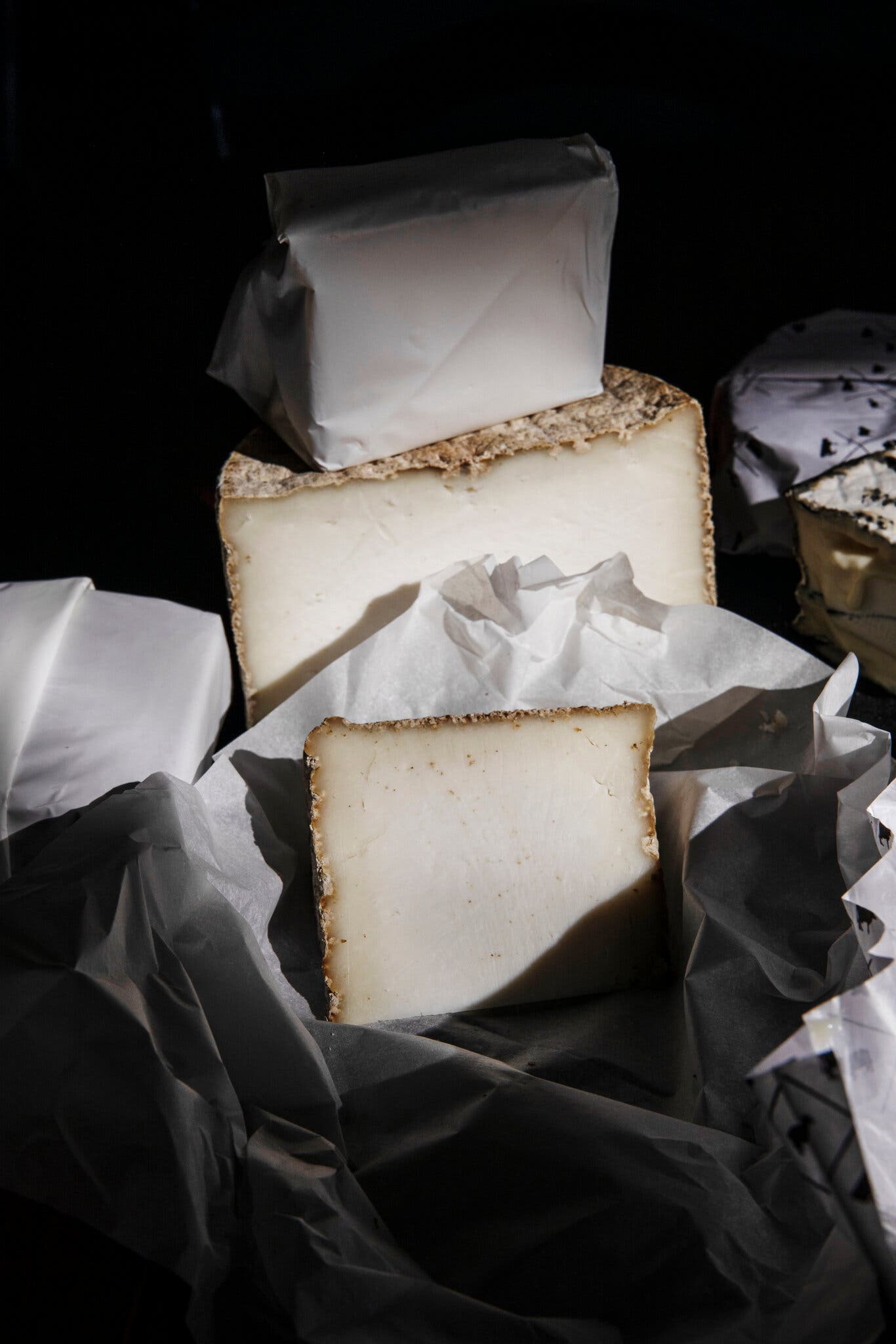 Three wedges of cheese are photographed in moody lighting.